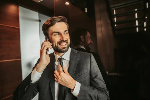 Optimistic male employer talking on smartphone inside — Stock Photo, Image