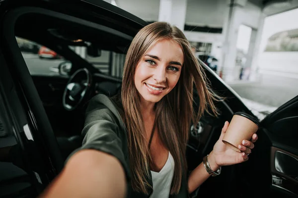 Chica alegre haciendo foto en coche moderno — Foto de Stock