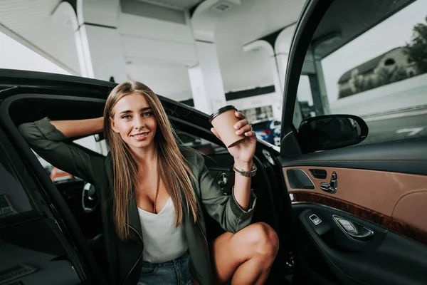 Chica saliente bebiendo café en el coche —  Fotos de Stock