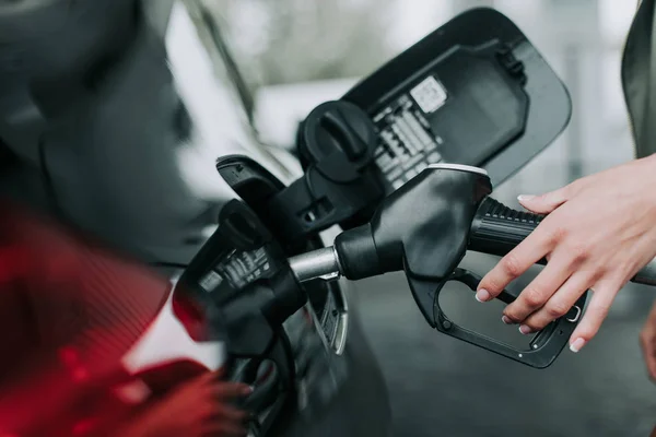 Mulher mão segurando bico bomba de gasolina ao ar livre — Fotografia de Stock