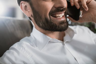 Sırıtan adam telefon görüşmesinde eğleniyor