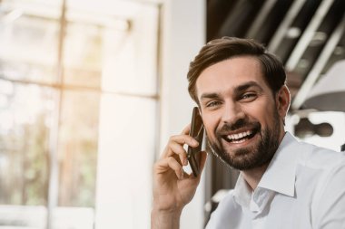 Gülen adam kapalı telefonla konuşuyor