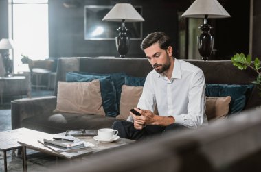 Konsantre adam akıllı telefon oturma odasında istismar