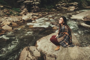 Taş Nehri'nin üzerinde oturan düşünceli genç kadın