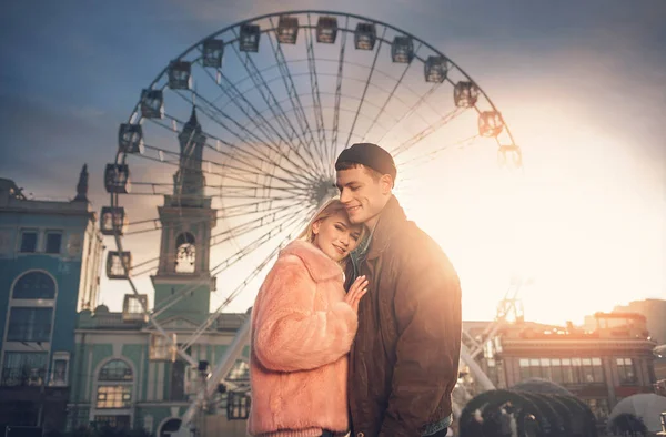 Beautiful loving couple cuddling in front of ferris wheel — Stock Photo, Image