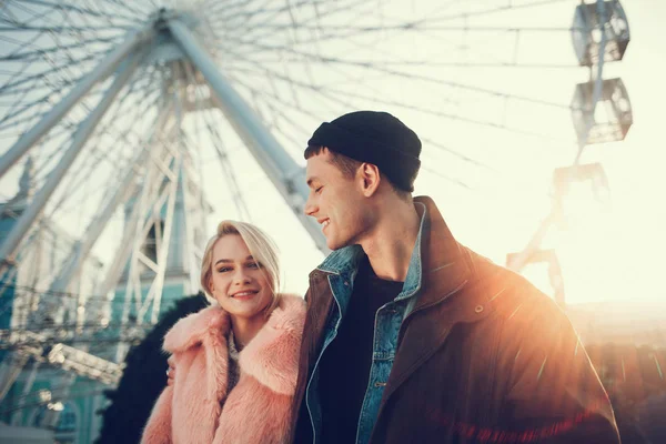 Beautiful couple standing in amusement park with ferris wheel on background — Stock Photo, Image