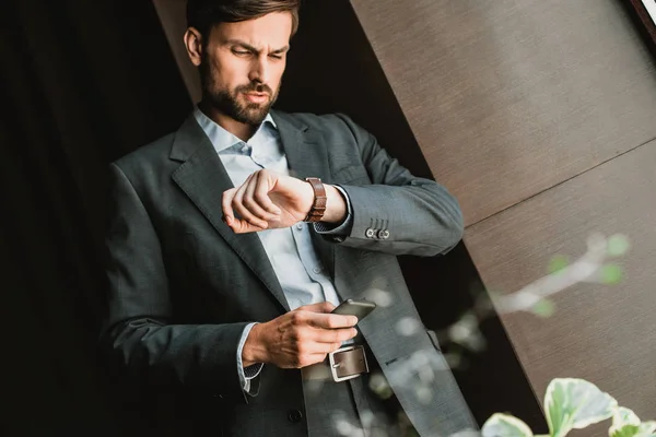 Concentrated businessman is checking time attentively outdoor — Stock Photo, Image