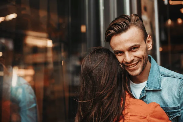 Uomo positivo abbracciare femmina durante il tempo libero al di fuori — Foto Stock