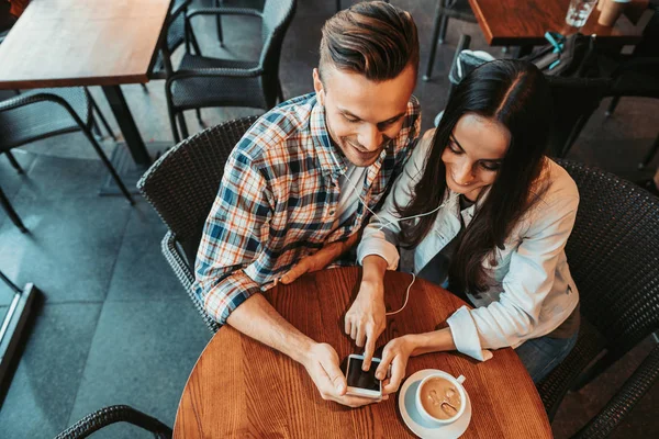Glad par tittar på mobilen på bordet — Stockfoto