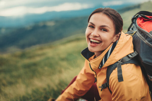 Cheerful smiling woman resting on the mountain slopes