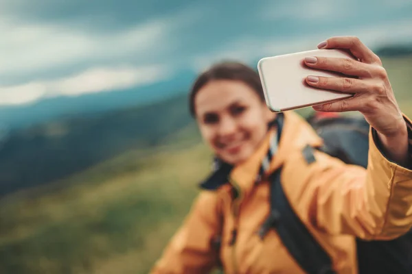 Selective focus of a phone in hands of a smiling woman