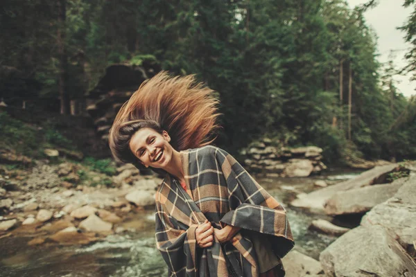 Cheerful young woman feeling happy on the bank of the mountain river