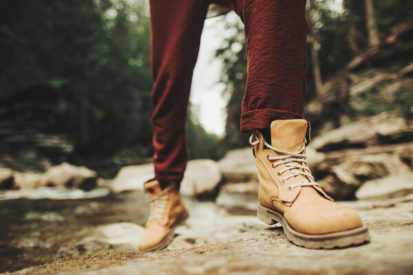 Close up of persons boots on the bank of mountaint river