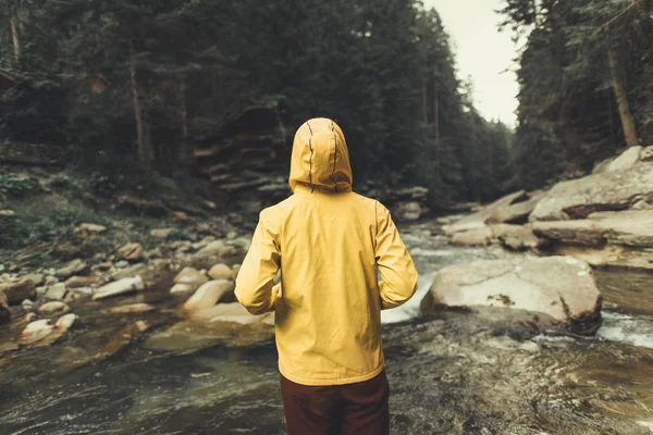 Bakifrån av en aktiv kvinna som står nära mountain river — Stockfoto