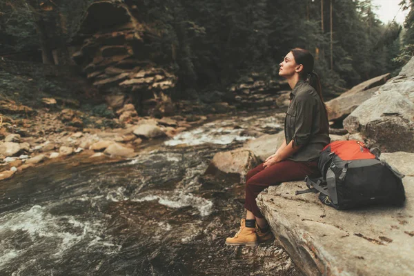Mírové žena sedící na kameni v blízkosti řeky — Stock fotografie