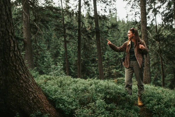 Glad flicka pekar på något intressant när du står i skogen — Stockfoto