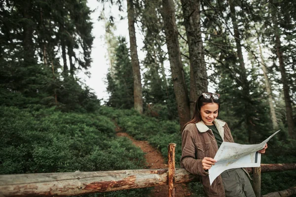 Красивая юная леди читает карту, опираясь на деревянный забор — стоковое фото