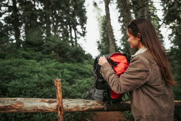 Красивая юная леди расстегивает рюкзак в лесу — стоковое фото