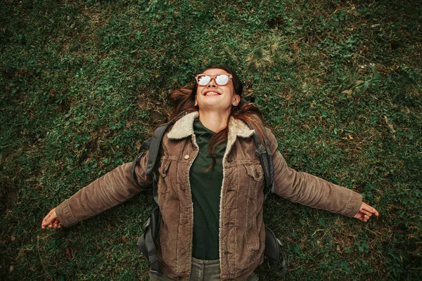 Glad ung kvinna liggande på rygg med armar utspridda — Stockfoto