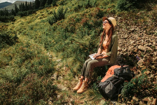 Charmig ung kvinna som sitter på klippan i grön äng — Stockfoto