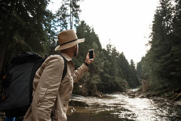 Молодой путешественник с рюкзаком и фотографирует природу — стоковое фото