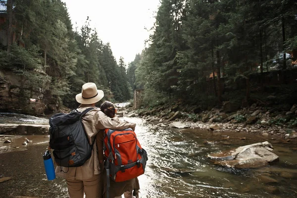 Couple de randonneurs serrant et regardant la rivière de montagne — Photo