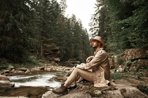 Lugn man bära snygga kläder och sitter på banken av floden — Stockfoto