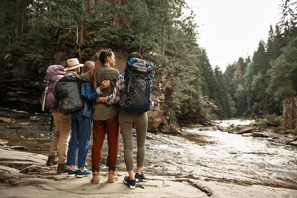 Čtyři přátelé, stojící vedle horské řeky a při pohledu na něj — Stock fotografie