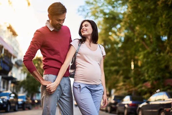 Lyckliga blivande föräldrar hålla händerna på boulevard — Stockfoto