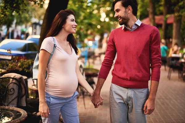 Liebendes Paar, das einander lächelnd ansieht, während es die Straße hinuntergeht — Stockfoto