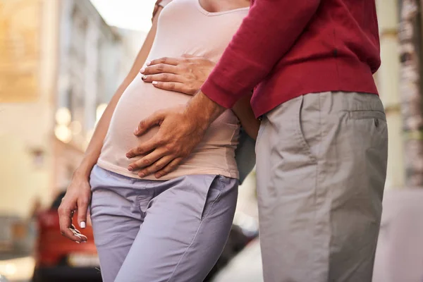 Lyckliga framtida föräldrar står på gatan och röra ung dam mage — Stockfoto