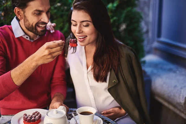 Cheerful bearded man feeding his charming girlfriend with tasty cake — Stock Photo, Image