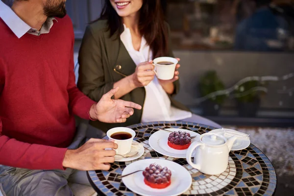 Young couple enjoying tea and chatting in outdoor cafe — Stock Photo, Image