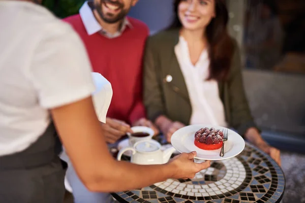 Waitress serving young beautiful couple in outdoor cafe — Stock Photo, Image