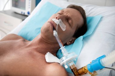Patient on mechanical ventilation lying in intensive care ward clipart