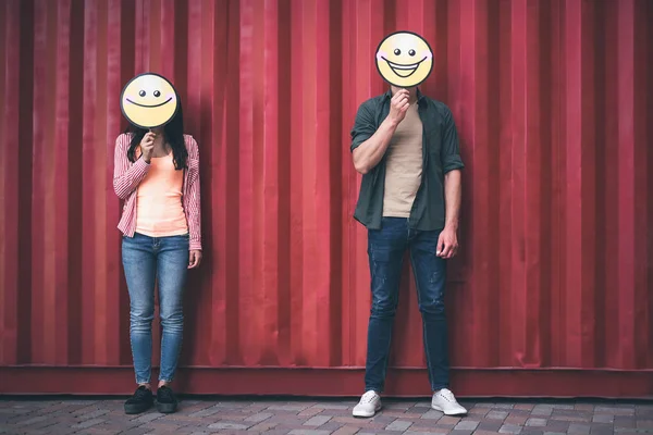 Zwei Menschen, die zusammen stehen und Gesichter hinter dem Lächeln verbergen — Stockfoto