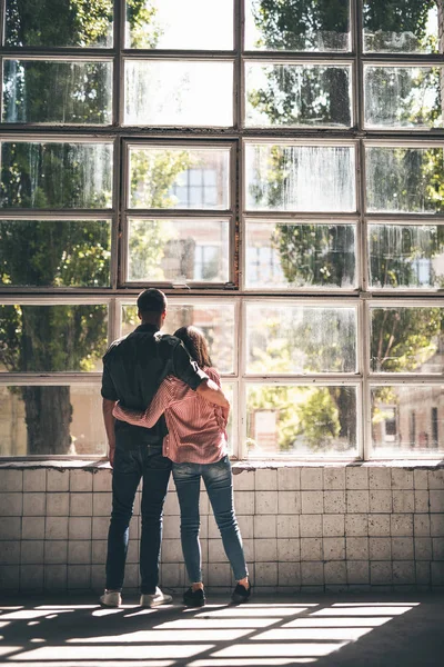 Two people hugging and looking out of the window