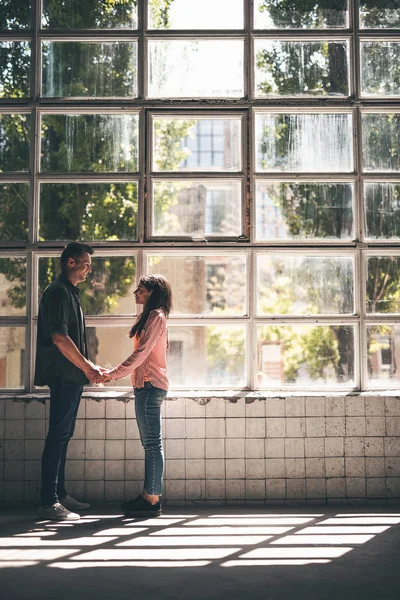 Romantisches Paar hält Händchen, während es im großen Raum steht — Stockfoto