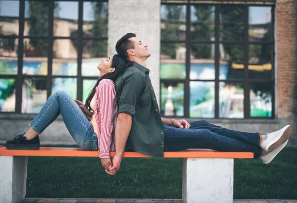 Entspannte Menschen, die gemütlich auf der Bank sitzen und Händchen halten — Stockfoto