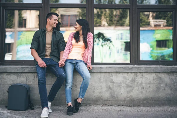 Volle Länge des glücklichen jungen Paares zusammen sitzen — Stockfoto