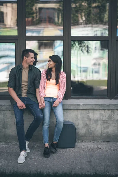 Zwei Personen, die auf der Brüstung sitzen und einander anlächeln — Stockfoto