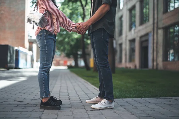 Paar dragen van jeans staan tegenover elkaar en hand in hand — Stockfoto