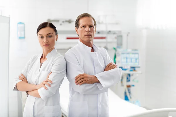 Confident medical workers with crossed arms posing in hospital room