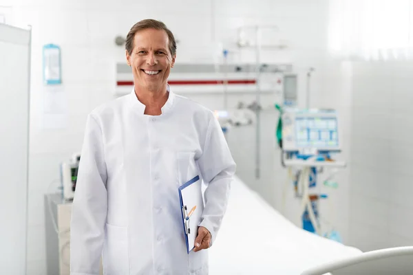 Alegre médico con forma médica de pie en la habitación del hospital — Foto de Stock