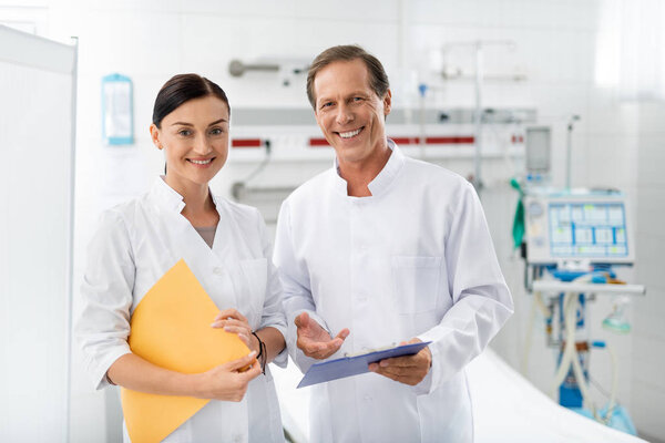 Laughing doctor and nurse posing at hospital room