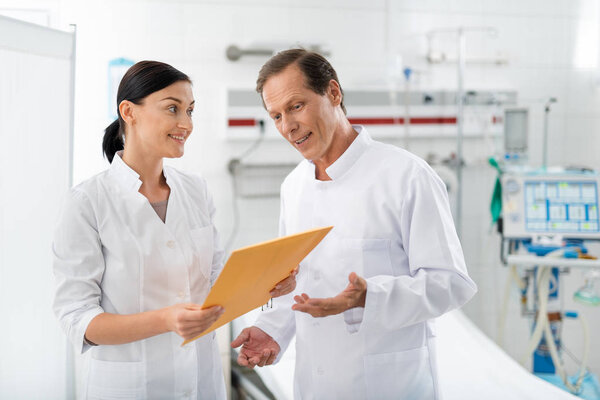 Cheerful doctor looking at orange envelope in nurse hands