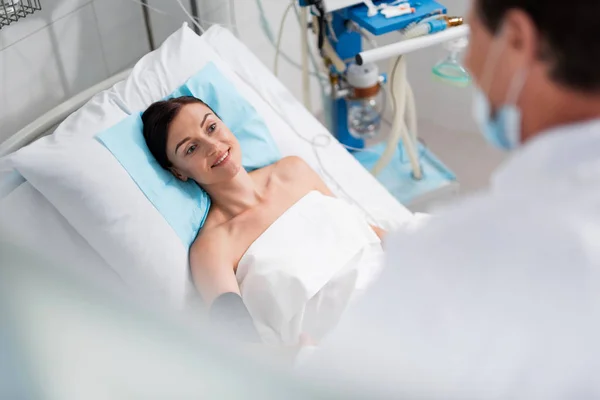 Senhora alegre ouvir médico enquanto deitado na cama do hospital — Fotografia de Stock