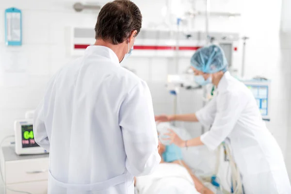Médico olhando para enfermeira enquanto ela coloca máscara de oxigênio no paciente — Fotografia de Stock