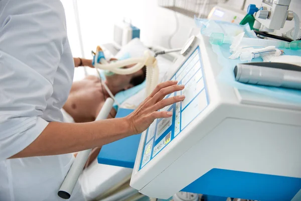 Läkare kontrollera andning maskin samtidigt sätta syrgasmask på patienten — Stockfoto