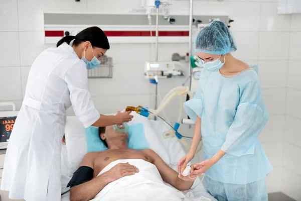 医師看護師彼の脈をチェックしながら患者に入れて酸素マスク — ストック写真